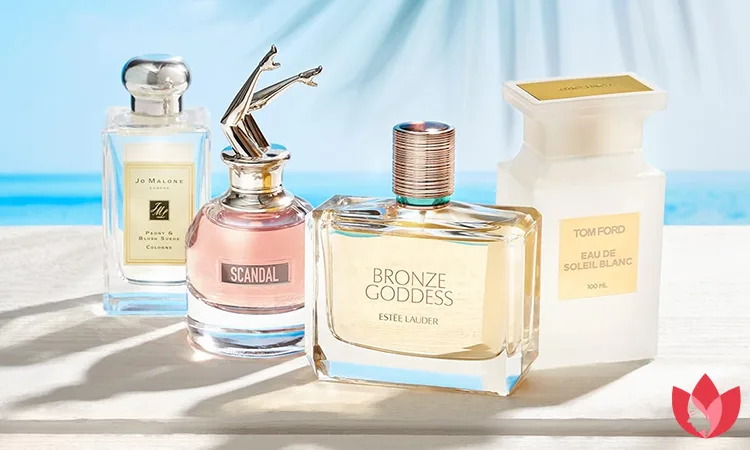 مجموعه‌ای از عطرهای تابستانی زنانه از برندهای جو مالون، تام فورد، اسکاندال و استی لادر روی میز کنار دریا
